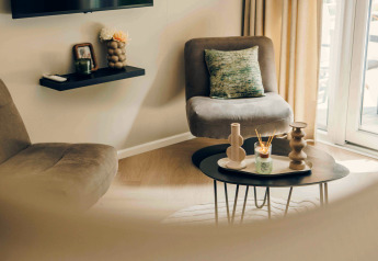 Sala moderna en una tiny house con sillones cómodos, mesa de centro decorativa y luz natural abundante.