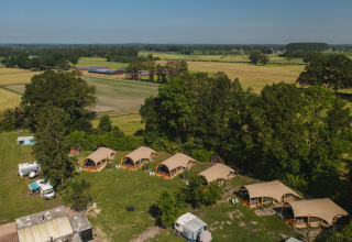 Luftfoto af ferieparken 't Schuttenbelt i Overijssel, Holland, med telte, campingvogne og grønne marker.