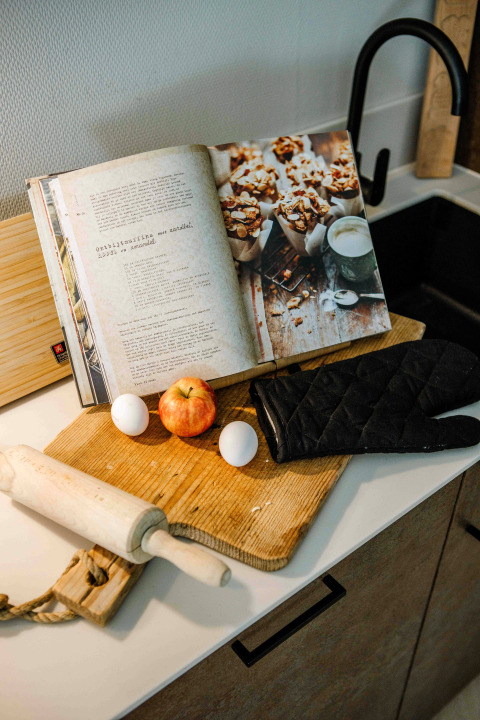 Cuisine de tiny house avec livre de recettes, pomme, œufs, rouleau à pâtisserie et gant de cuisson.