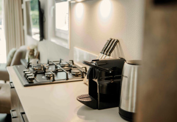 Angolo cottura moderno in una tiny house con piano cottura a gas, macchina da caffè e bollitore.