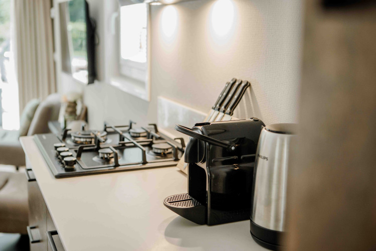Kompakte Küche in einem Tiny House mit Gasherd, Kaffeemaschine, Wasserkocher und Messerblock.
