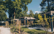 Vista esterna della Reeëndal Lodge al Veluwepark de Bosgraaf nei Paesi Bassi, circondata da alberi e natura.
