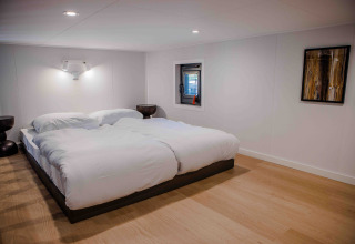 Moderne slaapkamer in een lodge met tweepersoonsbed, witte dekens, minimalistische meubels en kunst aan de muur.