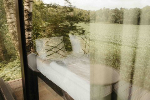 View through the window of Nokken NKN-18 Cabin at Wilsumer Berge, Germany, with nature outside.