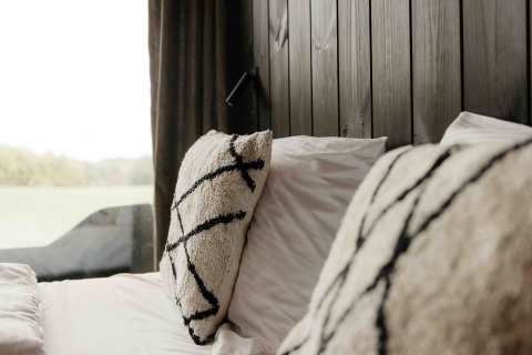 Primer plano de una cama acogedora con almohadas mullidas y pared de madera en Nokken NKN-18 Cabin, Wilsumer Berge.