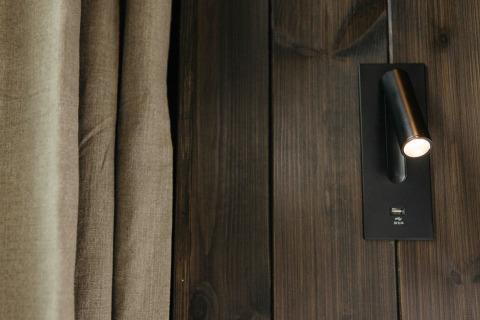 Close-up van wandlamp en USB-poort op donker houten paneel in de Nokken NKN-18 Cabin, Wilsumer Berge.