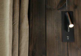 Primer plano de lámpara de lectura de pared y puerto USB en panel de madera oscura en Nokken NKN-18 Cabin, Wilsumer Berge.