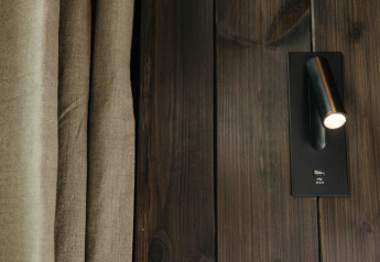 Closeup af vægmonteret læselampe og USB-port på mørkt træpanel i Nokken NKN-18 Cabin, Wilsumer Berge.