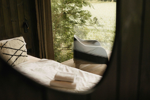 Vue intérieure de la Nokken NKN-18 Cabin aux Wilsumer Berge en Allemagne, avec lit et vue sur la nature.