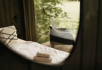 Vista interior de la Nokken NKN-18 Cabin en Wilsumer Berge, Alemania, con cama y vistas a la naturaleza.