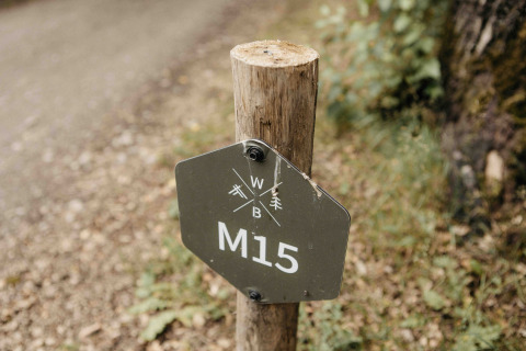 Trail marker sign displaying 'M15' outside Nokken NKN-18 Cabin at Wilsumer Berge in Germany.