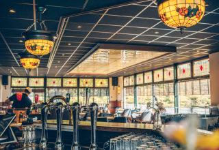 Interior de bar acogedor con lámparas de vidrieras en un alojamiento glamping rodeado de naturaleza.