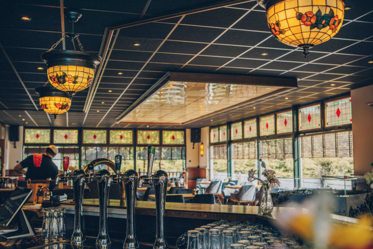 Interior de bar acogedor con lámparas de vidrieras en un alojamiento glamping rodeado de naturaleza.