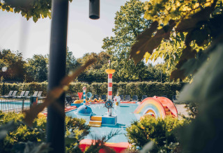 Bunter Kinderspielplatz mit Pool und Rutsche in einer Glamping-Unterkunft umgeben von Bäumen.