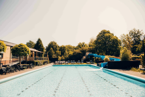 Piscine extérieure avec toboggan aquatique et transats dans un hébergement glamping lors d’une journée ensoleillée.