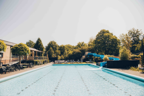 Piscina all'aperto con scivolo d'acqua e lettini presso una sistemazione glamping in una giornata di sole.