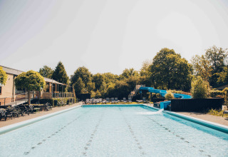 Outdoor-Pool mit Wasserrutsche und Liegestühlen bei einer Glamping-Unterkunft an einem sonnigen Tag.
