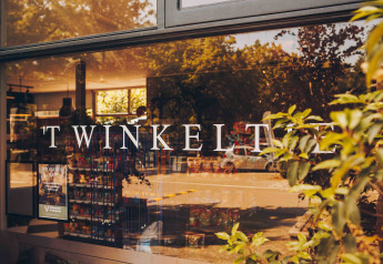 Entrée d’un hébergement glamping avec 'TWINKELT' sur la vitre et vue sur l’intérieur du magasin.