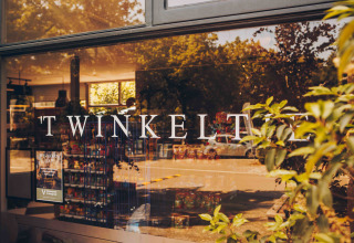 Entrance of a glamping accommodation showing 'TWINKELT' on the window with store interior visible inside.