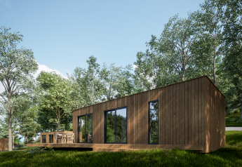 Moderne træ Eco Lodge med store vinduer og terrasse, omgivet af frodig skov under en klar himmel.