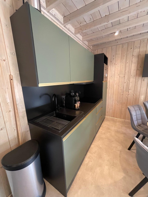 Moderne køkken med grønne skabe og sort bordplade i Eco Lodge ved Hameau de l'Ourthe, Belgien.