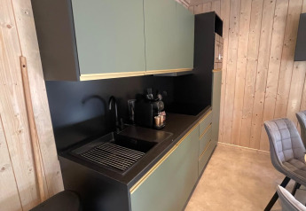 Cuisine moderne avec armoires vertes et plan noir à l’Eco Lodge du Hameau de l’Ourthe, Belgique.