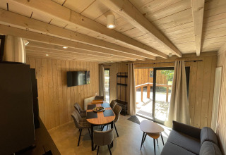 Intérieur en bois de l’Eco Lodge au Hameau de l’Ourthe en Belgique, avec coin repas et accès terrasse.