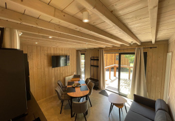 Intérieur en bois de l’Eco Lodge au Hameau de l’Ourthe en Belgique, avec coin repas et accès terrasse.
