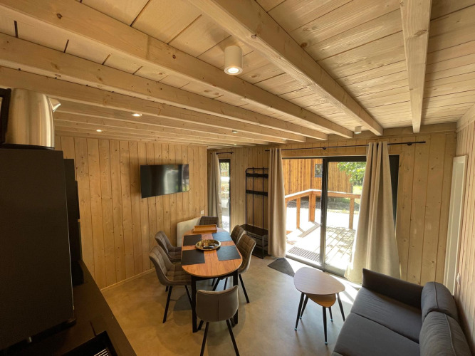 Træinteriør i Eco Lodge ved Hameau de l'Ourthe i Belgien, med spisebord, sofa og udsigt til terrassen.