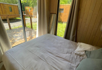 Soveværelse i en træbeklædt Eco Lodge på Hameau de l'Ourthe i Belgien med store vinduer og udsigt.