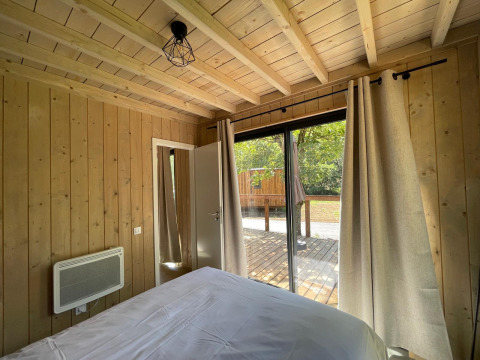 Slaapkamer in Eco Lodge bij Hameau de l'Ourthe, België, met houten wanden en uitzicht op het terras.