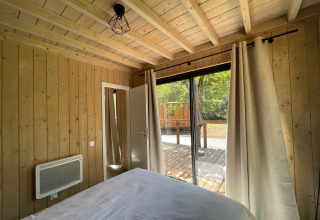 Soveværelse i Eco Lodge på Hameau de l'Ourthe i Belgien med trævægge og udsigt til terrasse.