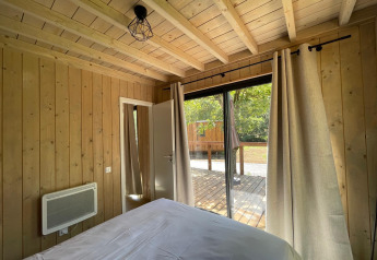Soveværelse i Eco Lodge på Hameau de l'Ourthe i Belgien med trævægge og udsigt til terrasse.
