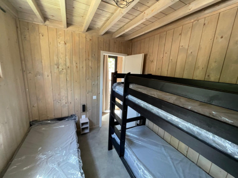 Chambre avec lits superposés et lit simple à l’Eco Lodge du Hameau de l’Ourthe, Belgique, murs en bois.