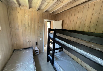 Værelse med køjeseng og enkeltseng på Eco Lodge ved Hameau de l'Ourthe, Belgien, med træpanelvægge.