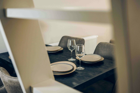 Table à manger moderne avec assiettes et verres à vin dans Tiny Loft, Veluwepark de Bosgraaf, Pays-Bas.