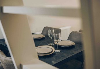 Mesa de comedor moderna con platos y copas de vino en Tiny Loft, Veluwepark de Bosgraaf, Países Bajos.