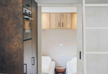 Casa diminuta moderna con cocina, altillo, y dos camas individuales separadas por una mesilla de noche.