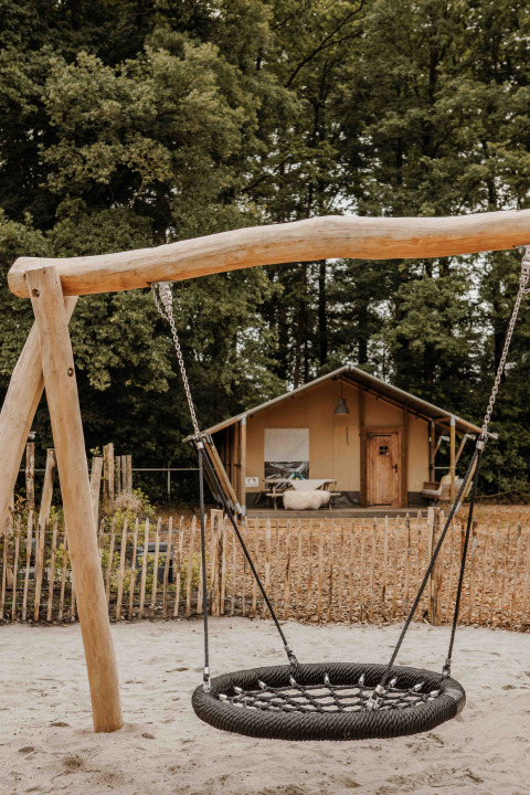 Ein Safarizelt mit einer runden Schaukel davor im Veluwepark de Bosgraaf in den Niederlanden.