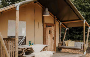 Tienda safari en Veluwepark de Bosgraaf, Países Bajos, con terraza de madera, banco y entorno natural.