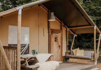 Safaritent in Veluwepark de Bosgraaf, Nederland, met houten terras, gezellige bank en buitenzitplaats.