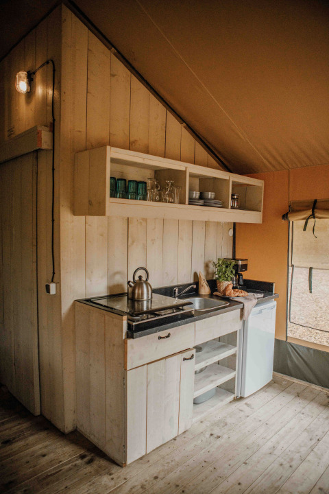 Pequeña cocina acogedora en una tienda safari en Veluwepark de Bosgraaf en Países Bajos, con detalles rústicos.