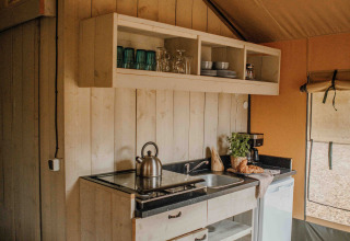 Pequeña cocina acogedora en una tienda safari en Veluwepark de Bosgraaf en Países Bajos, con detalles rústicos.
