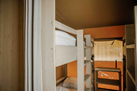 Vista interior de una tienda safari con literas y luz natural en Veluwepark de Bosgraaf, Países Bajos.