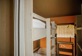 Vista interior de una tienda safari con literas y luz natural en Veluwepark de Bosgraaf, Países Bajos.