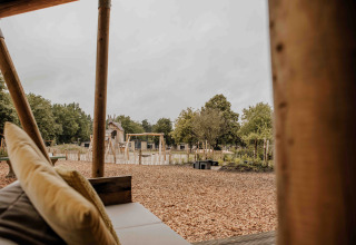 Udsigt fra en safaritelts veranda på Veluwepark de Bosgraaf, med legeplads og natur i Holland.