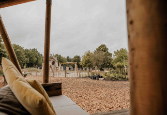 Zicht vanuit een safaritent op Veluwepark de Bosgraaf, Nederland, met speeltuin en natuur.