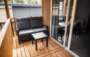 Wooden terrace with gray bench and table at Loggia Wood in Eurocamping Vessem BV, Netherlands