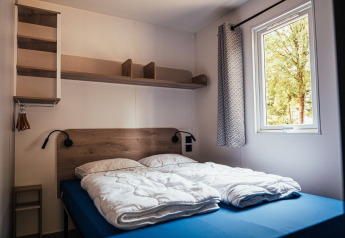Moderne soveværelse på Loggia Wood, Eurocamping Vessem BV, Holland, med dobbeltseng og vindue.