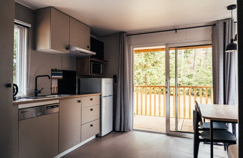 Modernes Kücheninterieur einer Lodge mit Schiebetür zur Holzterrasse, Loggia Wood, Eurocamping Vessem, Niederlande.